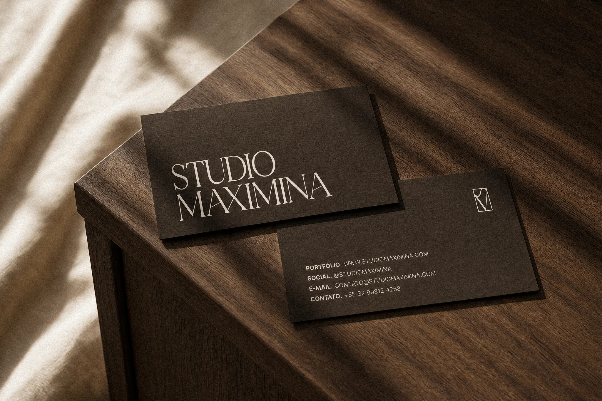 Cartões de visita do Studio Maximina sobre uma mesa de madeira